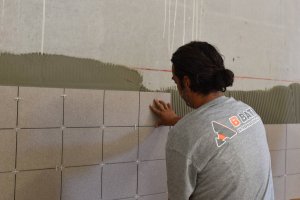 Compagnon B BATI qui pose du carrelage